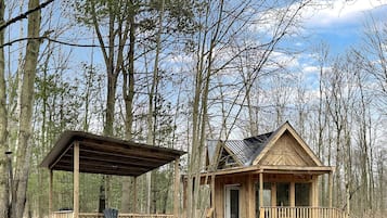 Une cabane en bois avec un porche, un espace abrité et une petite terrasse.