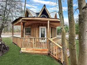 A wooden cabin with a porch, a door, and a small window. - Cozy Secluded Tiny Cabin for a True Getaway in the Outdoors Surrounded by Nature in Simcoe, Ontario (Simcoe)