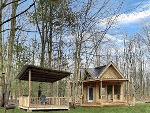 A wooden cabin with a porch, a covered area, and a small deck.