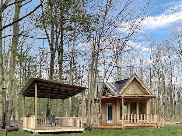 A wooden cabin with a porch, a covered area, and a small deck.