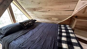 Une chambre à coucher avec un lit, un tapis à carreaux et un coussin orné d’un motif textuel.