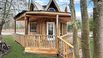 A wooden cabin with a porch, a door, and a small window.