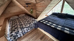 A wooden cabin interior with two beds, a hanging plant, and a window. - Cozy Secluded Tiny Cabin for a True Getaway in the Outdoors Surrounded by Nature in Simcoe, Ontario (Simcoe)