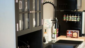 Een keuken met een zwart kastje, een wit aanrechtblad en een magnetron.