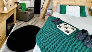 Un hébergement sous tente comprenant un lit, un petit coin salon, une cheminée et une fenêtre.