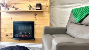 Un espace de vie chaleureux avec une cheminée, un canapé, un téléviseur et une structure ressemblant à une tente.