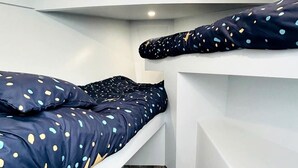 A compact room with two bunk beds, each with a polka dot duvet. - Peaceful Boat Retreat with Luxury Interior with Hot Tub in Cocagne, New Brunswick (Cocagne)