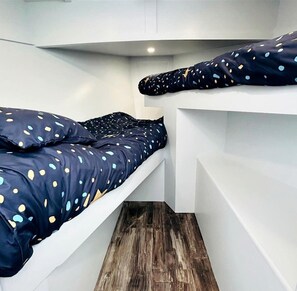 A compact room with two bunk beds, each with a polka dot duvet. - Peaceful Boat Retreat with Luxury Interior with Hot Tub in Cocagne, New Brunswick (Cocagne)