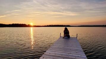 A wooden pier extending into calm water with a sunset in the background.