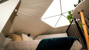 A tent-like structure with a bed inside, a radiator, and a plant.