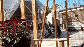 Eine Holzterrasse mit einem Blumentopf und einer Kerze, mit Blick auf einen Poolbereich mit Zeltdach.