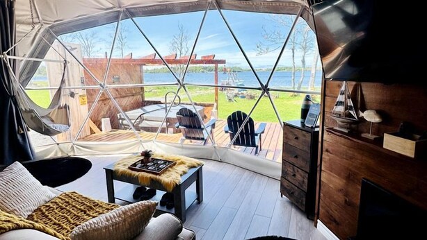 Una carpa con vistas a una terraza de madera y mobiliario exterior.