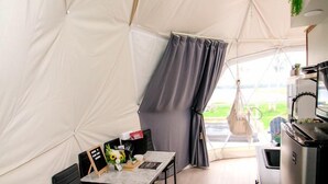 Alojamiento con carpa, zona de comedor, cocina y vistas al exterior.