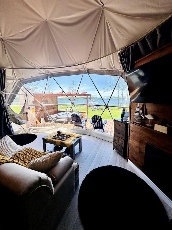 A tent with a view of a wooden deck and outdoor seating.