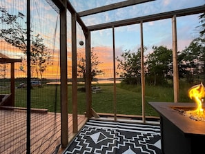 A deck with a fire feature, a patterned rug, and a view of a sunset.