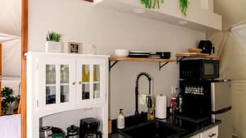 A compact kitchen with white cabinetry, a black countertop, and a microwave.