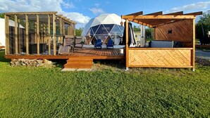 Estructura de domo geodésico con terraza y zona de estar de madera.