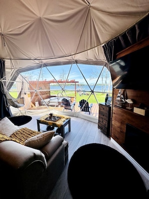 Una carpa con vistas a una terraza de madera y mobiliario exterior.