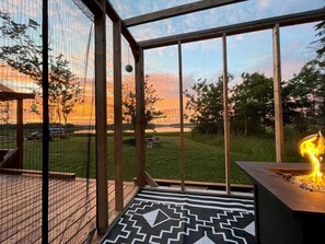 A deck with a fire feature, a patterned rug, and a view of a sunset. - Nova Scotia Dome with Private Hot Tub for Relaxing Retreats in Antigonish, Canada (Antigonish)