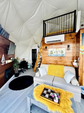 Una sala de estar acogedora con un sofá, una mesa de centro, una chimenea y una pared de madera.