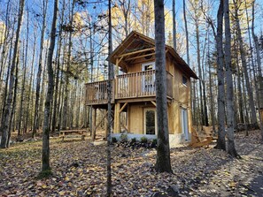 Una cabaña de madera con balcón, rodeada de un bosque.