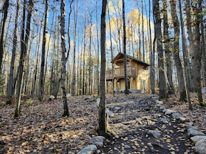 Une cabane au milieu d’une forêt, accessible par un sentier de terre.