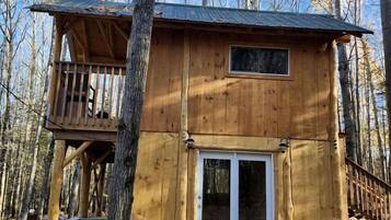 Une cabane en bois dotée d’un balcon, d’une porte-fenêtre coulissante et d’une terrasse.