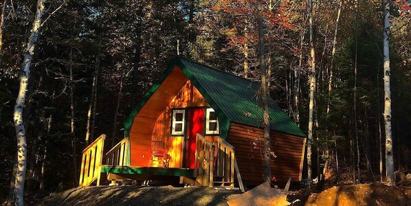 Une cabane avec un toit triangulaire, une véranda et une porte bien visible.