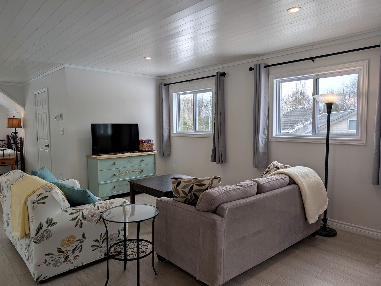 Un salon avec un canapé, un téléviseur, une petite table et une lampe.