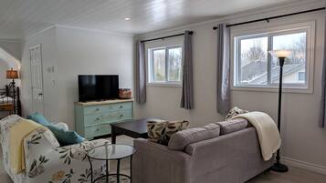 A living room with a sofa, a TV, a small table, and a lamp.