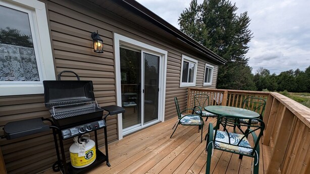 Une terrasse en bois avec un barbecue, des chaises et une table.