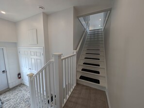 A staircase with white railings and a wooden floor leading to a landing. - Aspen Acres Cabin with BBQ and Private Deck (Chatsworth)