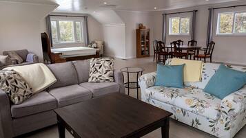 A spacious living room with a sofa, a coffee table, and a floral-patterned couch.