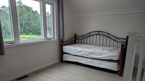 Une chambre avec un lit, une fenêtre et une vue sur les arbres.