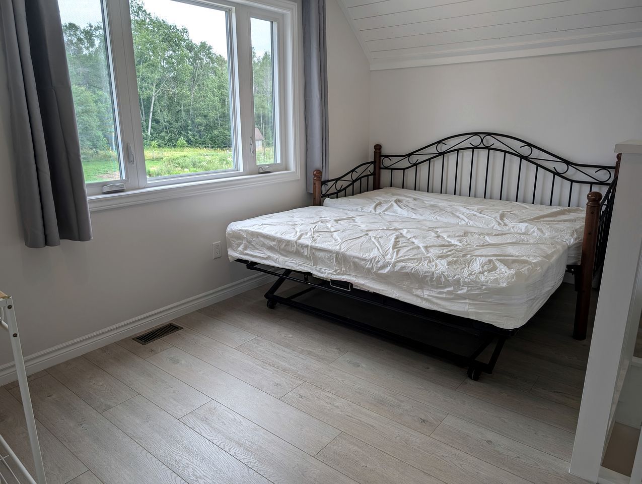 Una habitación con cama, ventana con cortinas y vistas a zonas verdes.