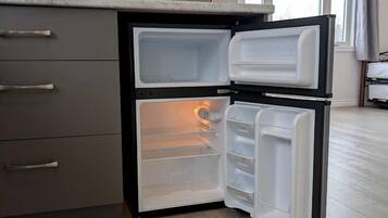 Eine kompakte Küche mit einer eingebauten Mikrowelle, einem Kühlschrank mit Gefrierfach und Holzboden.