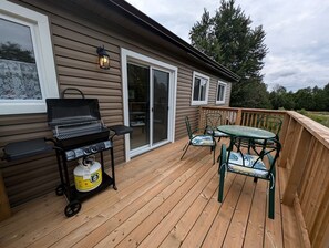 Une terrasse en bois avec un barbecue, des chaises et une table.