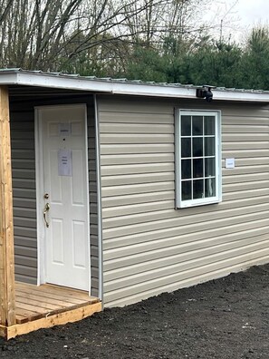 Un bâtiment d’un seul étage avec une porte blanche et une petite fenêtre.