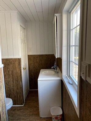 Een kleine badkamer met een wit wastafel, toilet en raam.