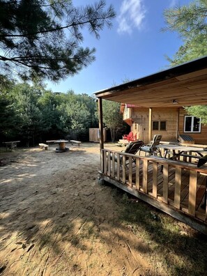 A wooden deck with outdoor furniture, a covered patio, and a house with a window.