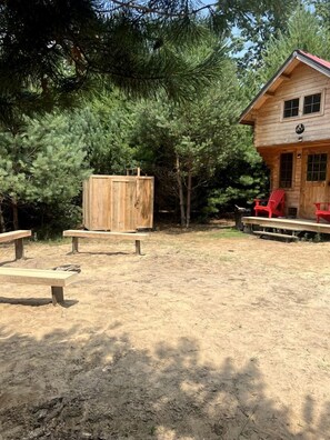 Une cabane dotée d’une terrasse en bois, d’un espace salon couvert et d’une grande structure en bois.