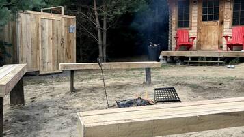 A wooden cabin with a porch, a fire pit, and outdoor seating.