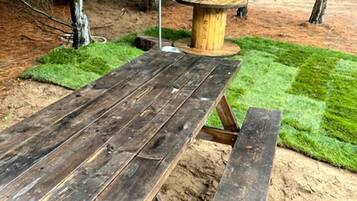 A wooden picnic table with benches in a wooded area.