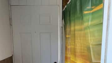 A white door with a brass doorknob, a wooden floor, and a colorful curtain partially covering a window.