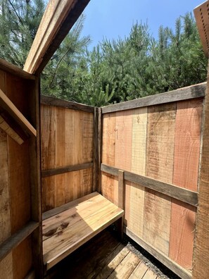 Un espace extérieur aménagé avec des sièges en bois, comprenant un banc et une table, le tout entouré d’une clôture en bois.