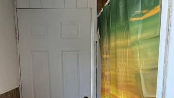 A white door with a brass doorknob, a wooden floor, and a colorful curtain partially covering a window.