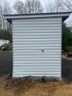 A metal shed with horizontal siding, a small door, and a vent on the roof. - Ontario Glamping Cabin, Perfect for Discovering Port Dover (Simcoe)