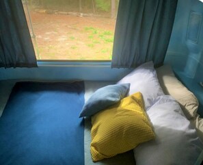 Un lit avec un matelas bleu, un oreiller et un coussin jaune.