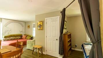 A room with a bed, a desk, a chair, a small table, and a door.