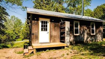 Une petite cabane en bois avec une porte d’entrée, des fenêtres et une véranda.